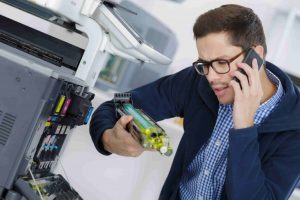 technicien au téléphone réparant un photocopieur